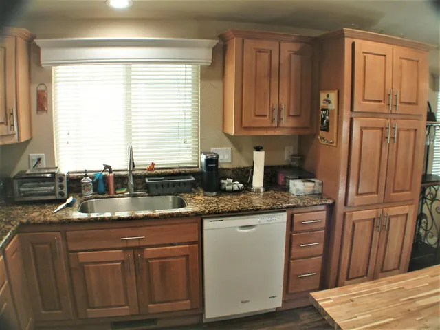 a kitchen with granite countertop cabinets stainless steel appliances a sink and a window