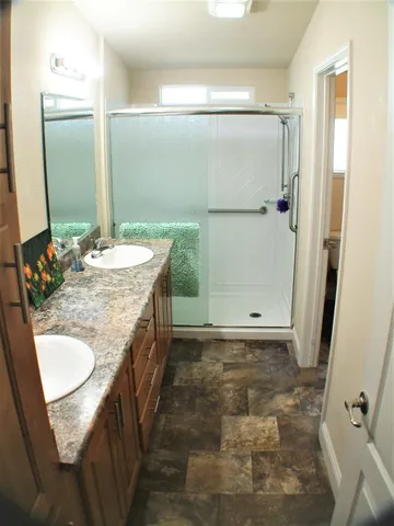 a bathroom with a granite countertop sink a mirror and shower