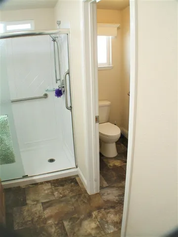 a bathroom with a granite countertop shower and a toilet
