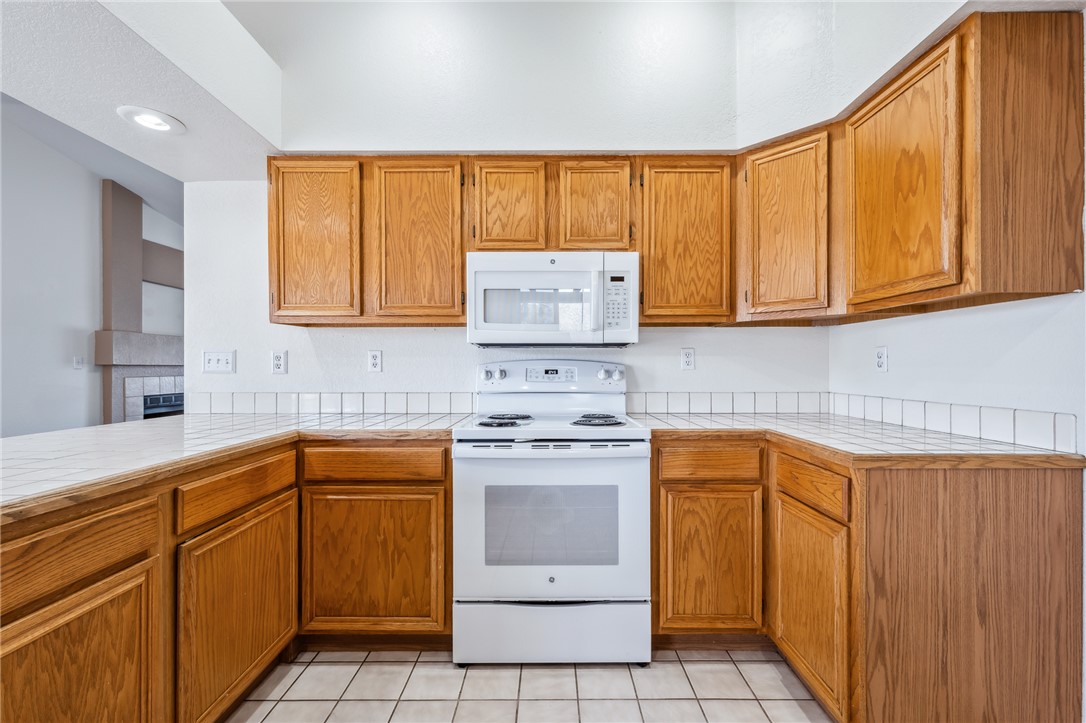 2524 South Ridge Avenue Bullhead City, AZ 86429 - Photo 21 of 64 Kitchen featuring white appliances, tile countertops, and brown cabinetry