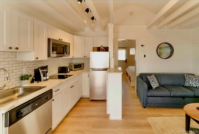 a living room with stainless steel appliances granite countertop furniture a sink a stove and a window