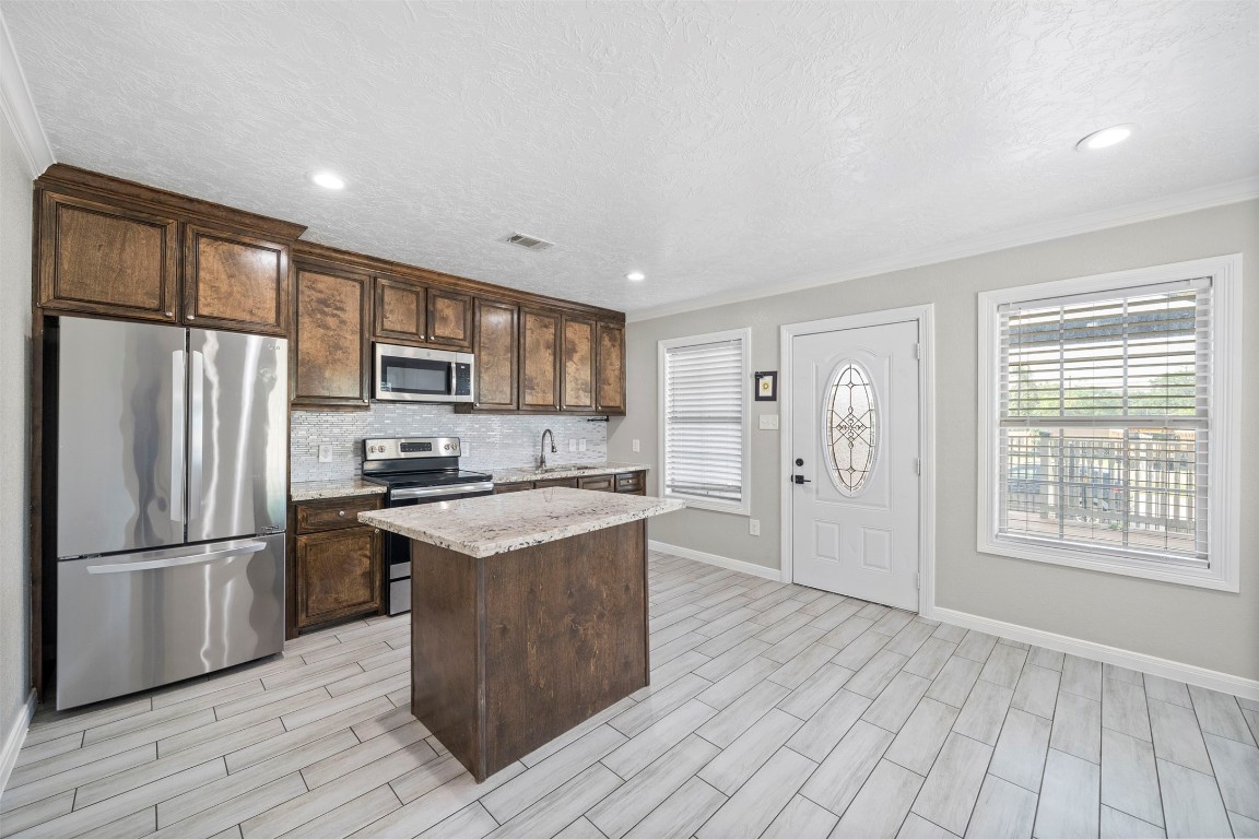 7941 Goode Street Houston, TX 77012 - Photo 17 of 26 a kitchen with stainless steel appliances granite countertop a refrigerator a stove top oven a sink and dishwasher with wooden floor