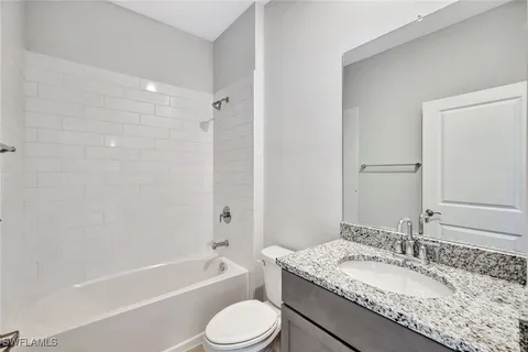 a bathroom with a granite countertop sink toilet mirror and bathtub