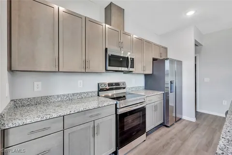 a kitchen with stainless steel appliances granite countertop a stove a refrigerator and a microwave