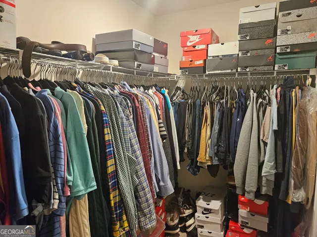 a view of walk in closet with clothes and shoes