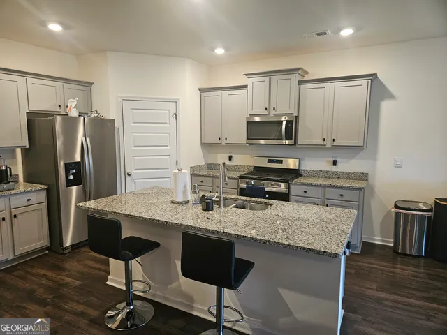 a kitchen with stainless steel appliances granite countertop a stove top oven a refrigerator a sink and a stove