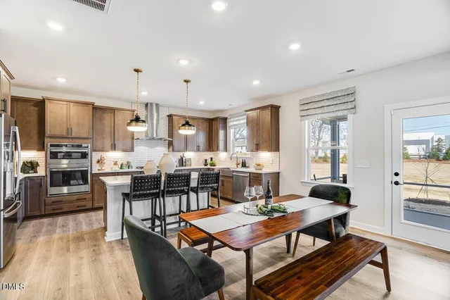 a kitchen with stainless steel appliances a stove a sink a microwave a refrigerator and chairs