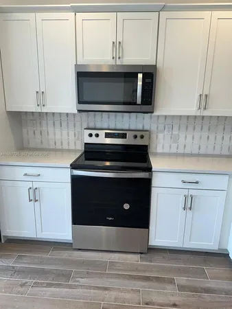 a kitchen with white cabinets and appliances