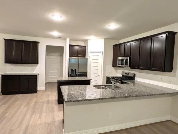 a large kitchen with granite countertop a stove a sink and a microwave