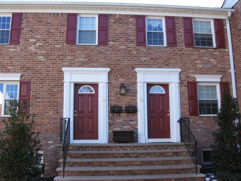 a front view of a brick building with a clock on the walls