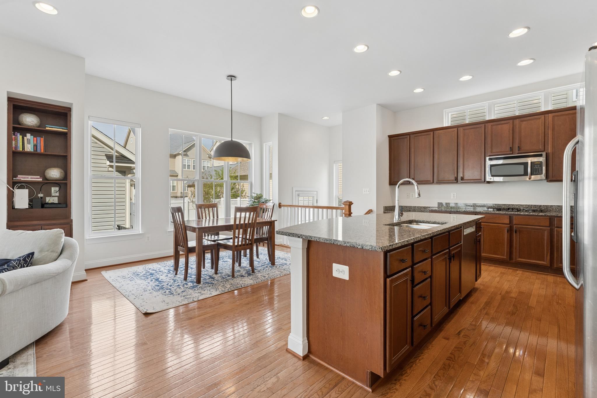 23342 Higbee Lane Brambleton, VA 20148 - Photo 22 of 73 a kitchen with stainless steel appliances granite countertop a stove top oven a sink dishwasher a dining table and chairs with wooden floor