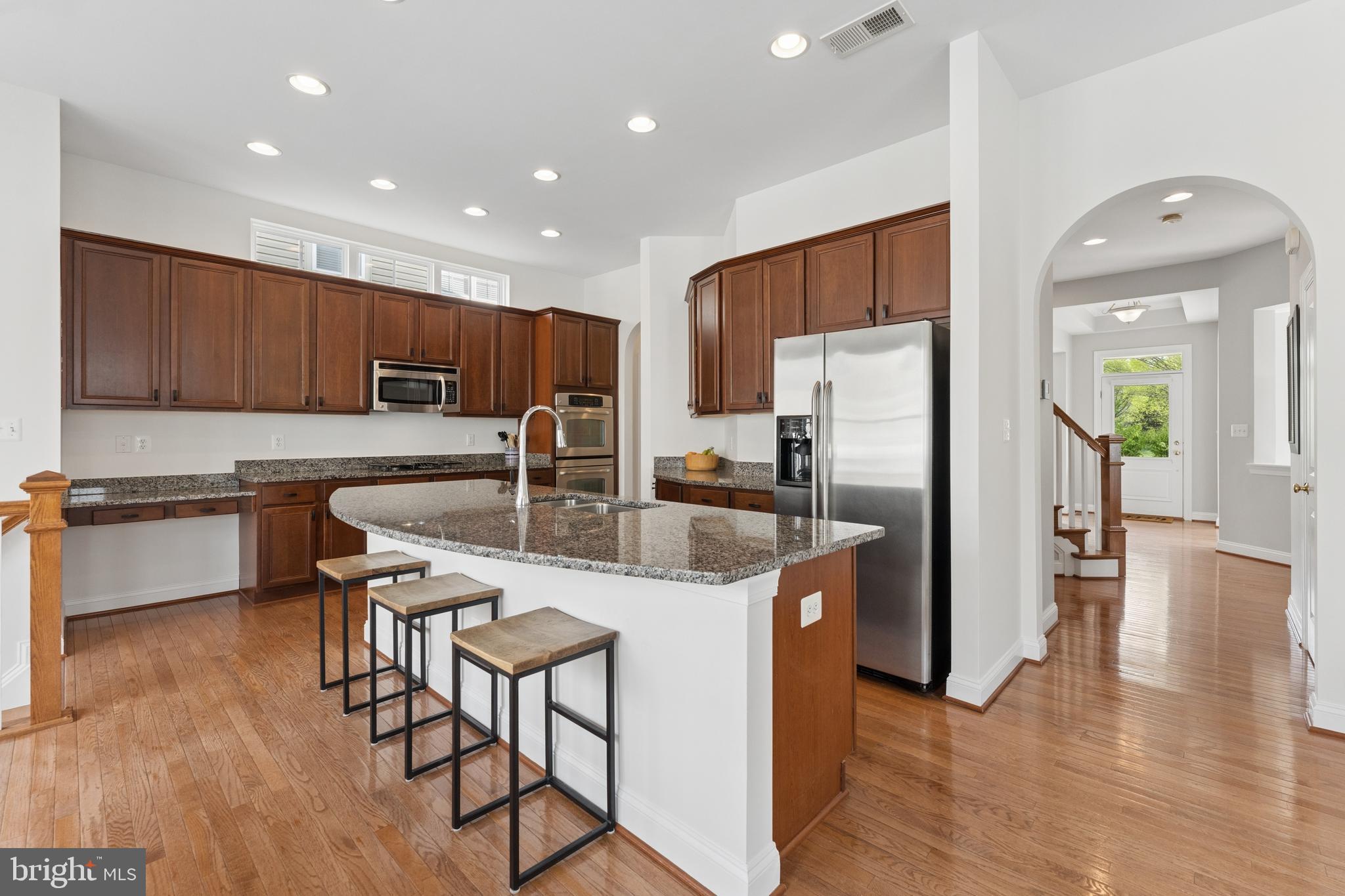 23342 Higbee Lane Brambleton, VA 20148 - Photo 25 of 73 a kitchen with stainless steel appliances granite countertop a refrigerator a stove a sink a dining table and chairs with wooden floor