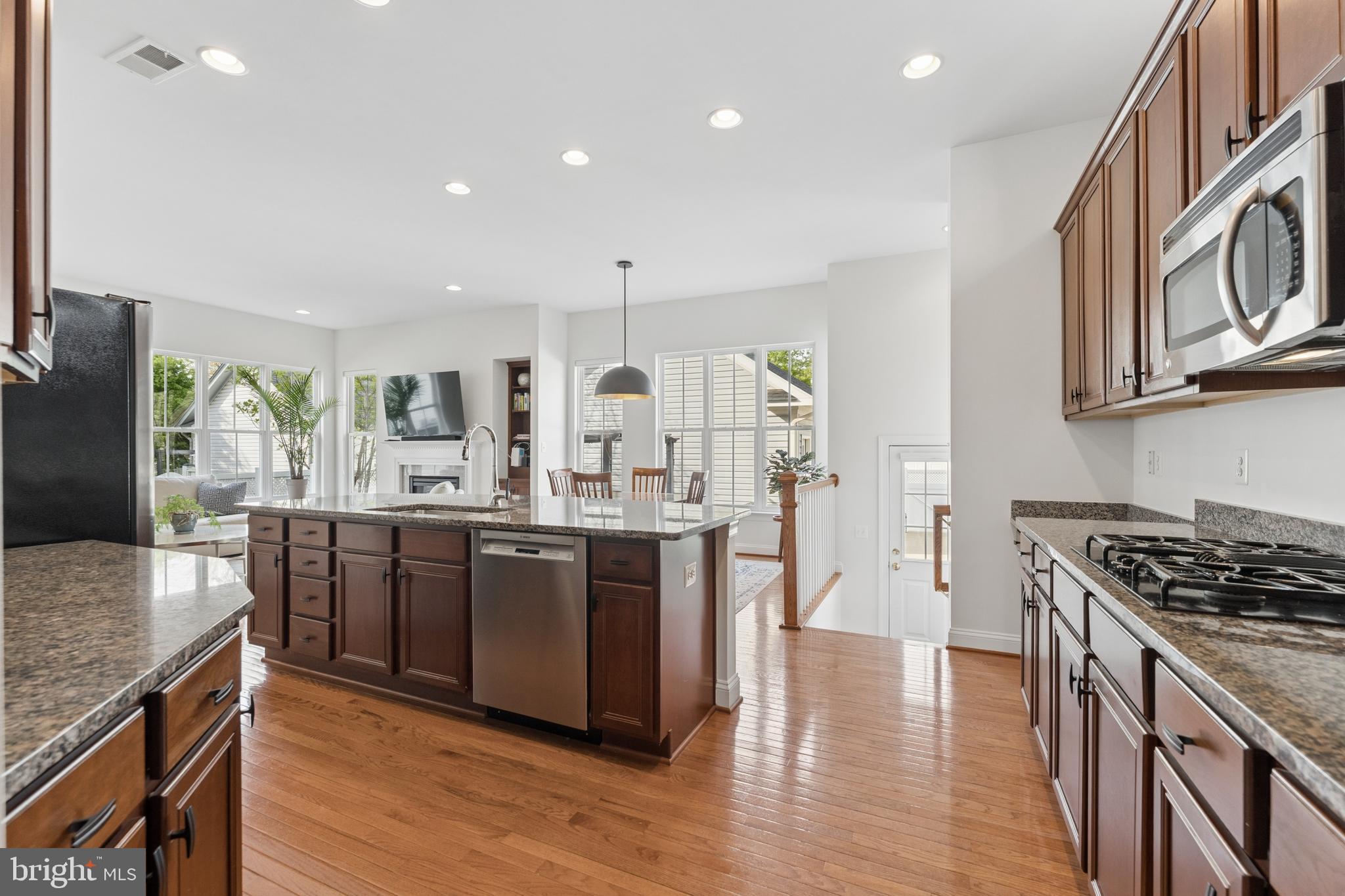 23342 Higbee Lane Brambleton, VA 20148 - Photo 27 of 73 a kitchen with stainless steel appliances granite countertop a stove top oven a sink dishwasher a dining table and chairs with wooden floor