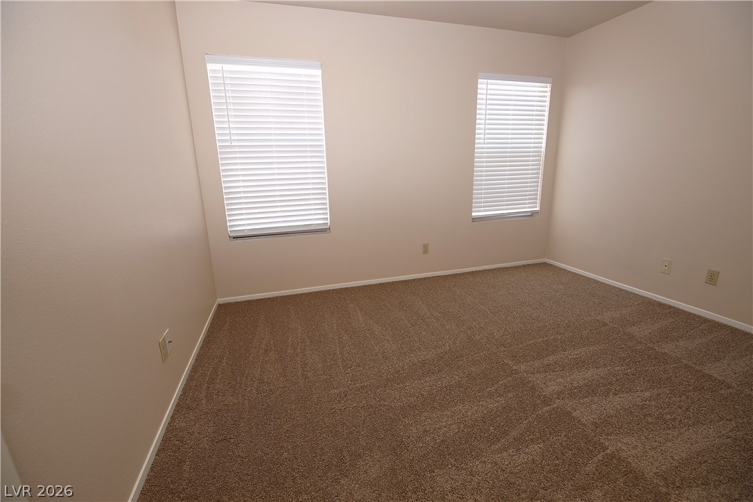 8220 Maplestar Road Las Vegas, NV 89128 - Photo 23 of 29 A spacious room offers comfortable carpet flooring and ample natural light from two large windows.