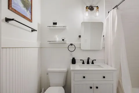 a white bathroom with a sink a toilet and a mirror