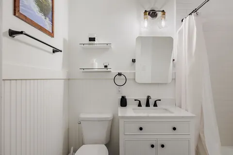 a white bathroom with a sink a toilet and a mirror