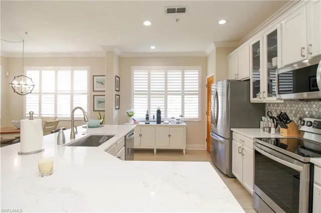 a large white kitchen with a large window a sink and stainless steel appliances