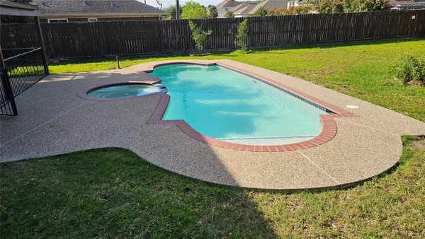 a view of a swimming pool with a patio and wooden fence