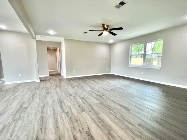 a view of an empty room with wooden floor and a window
