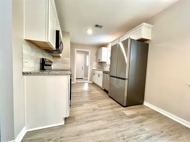 a kitchen with stainless steel appliances granite countertop a refrigerator a stove and a sink