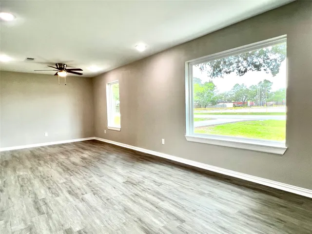 an empty room with wooden floor and windows