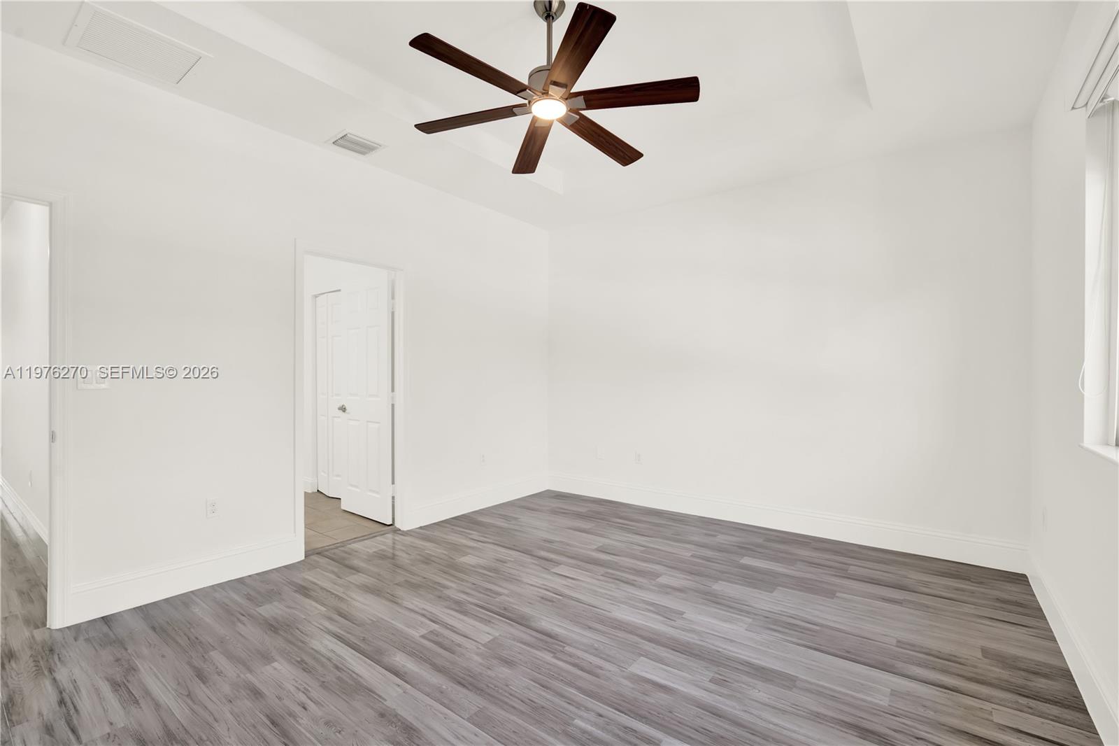 9243 Southwest 227th Terrace Cutler Bay, FL 33190 - Photo 11 of 32 an empty room with wooden floor and a ceiling fan