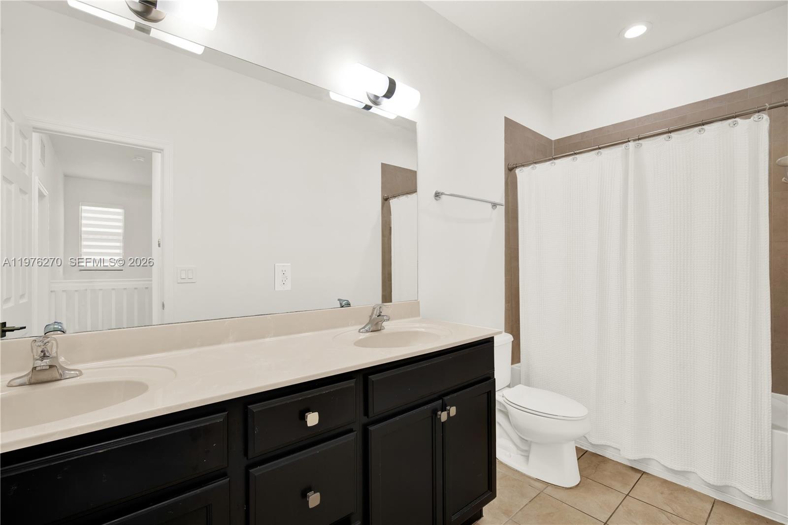 9243 Southwest 227th Terrace Cutler Bay, FL 33190 - Photo 14 of 32 a bathroom with a double vanity sink toilet and a mirror