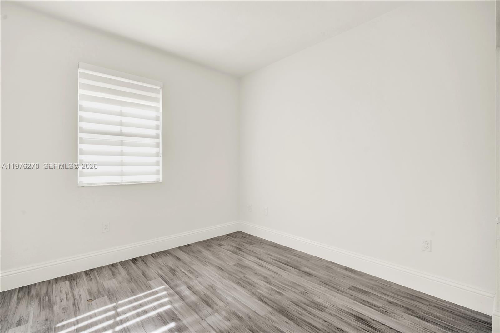 9243 Southwest 227th Terrace Cutler Bay, FL 33190 - Photo 15 of 32 an empty room with wooden floor and windows