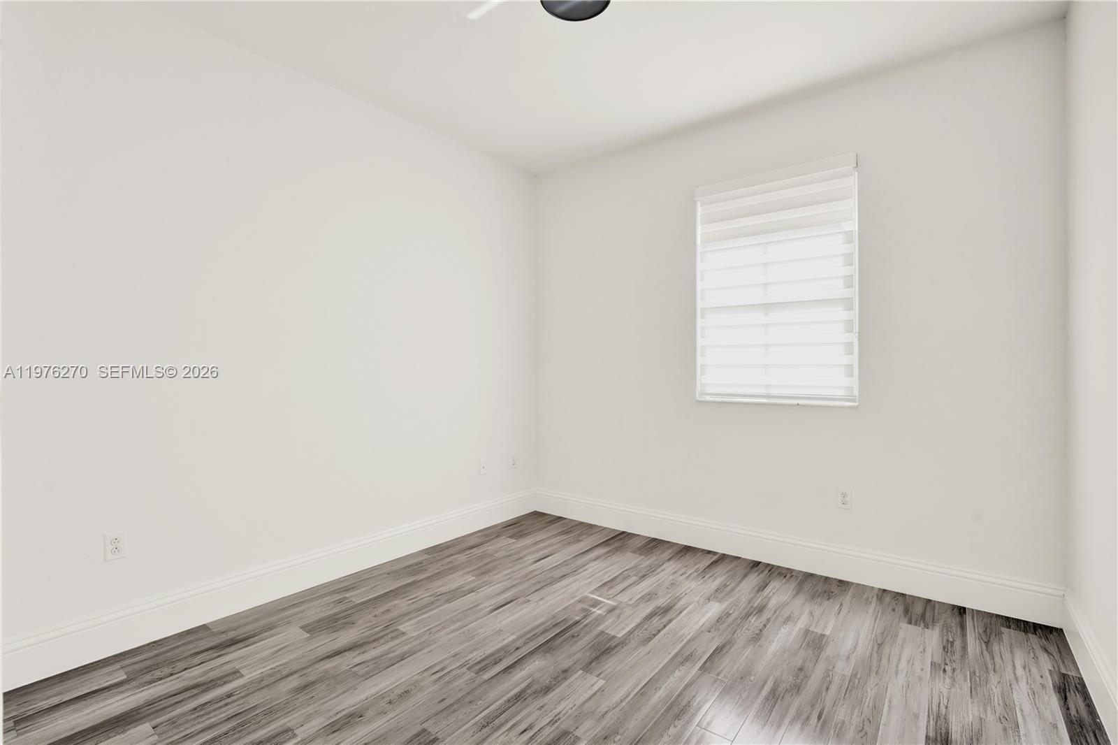 9243 Southwest 227th Terrace Cutler Bay, FL 33190 - Photo 16 of 32 an empty room with wooden floor and windows