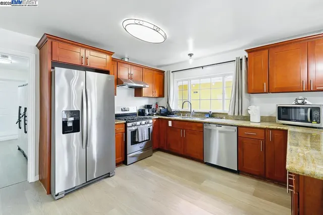 a kitchen with stainless steel appliances granite countertop a refrigerator a sink dishwasher a stove and a refrigerator