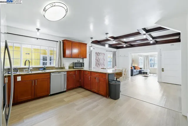 a large kitchen with stainless steel appliances granite countertop a large counter top a sink a stove a chimney a refrigerator and cabinets