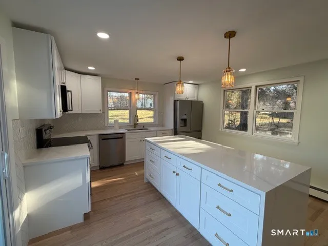 a kitchen with granite countertop white cabinets and a wooden floor
