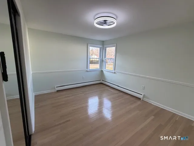 an empty room with wooden floor and windows