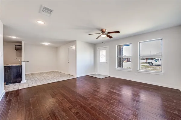 a view of an empty room with window and wooden floor