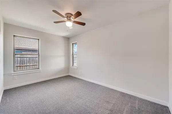 an empty room with a window and a ceiling fan