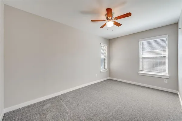 an empty room with ceiling fan and window
