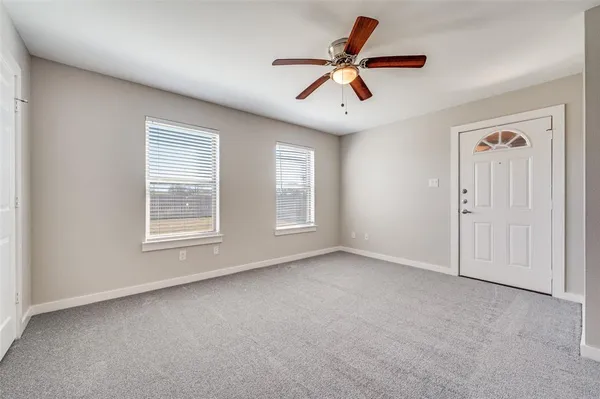 an empty room with windows and fan