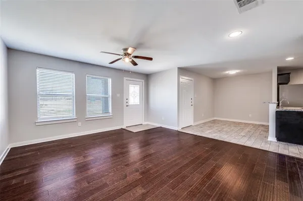 a view of an empty room with a window and wooden floor