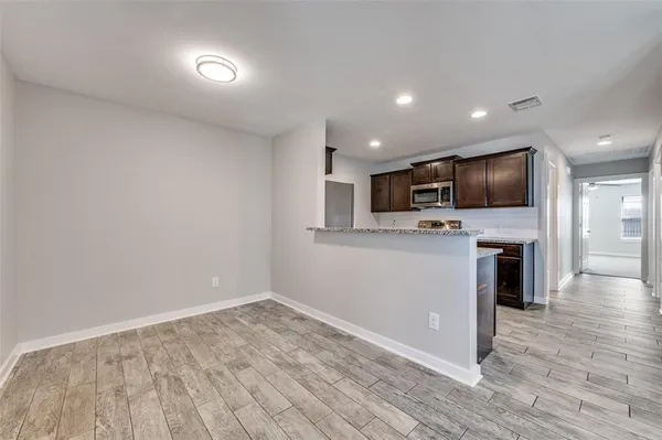 a view of kitchen with microwave oven stove and wooden floor