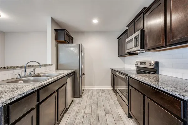 a kitchen with stainless steel appliances granite countertop a sink stove and refrigerator