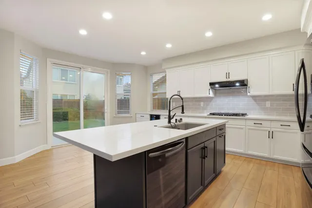a kitchen with a sink and large mirror with wooden floor