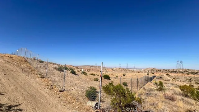 a view of a dry field with mountains in the background
