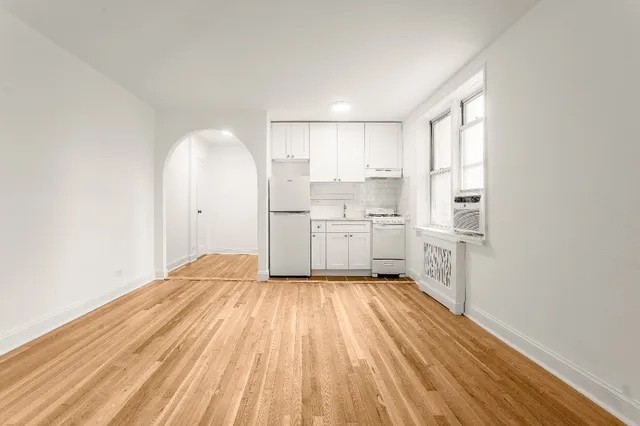 a kitchen with white cabinets appliances wooden floor and a window
