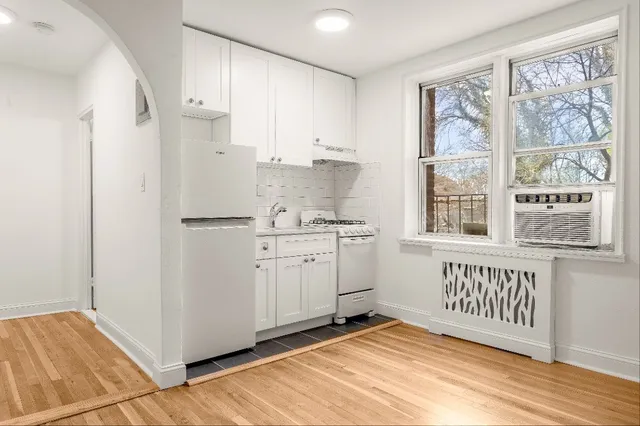 a view of a kitchen with white cabinets and wooden floor
