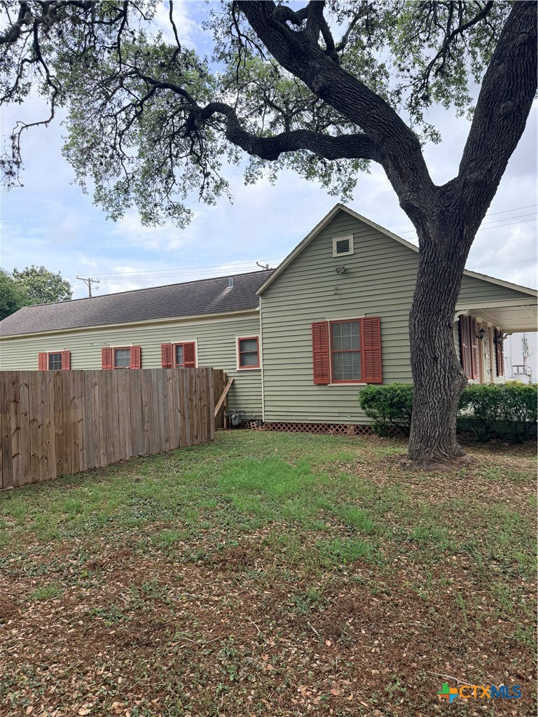 607 North Bridge Street Victoria, TX 77901 - Photo 3 of 8 a view of backyard of house with large tree and wooden fence