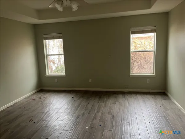 an empty room with wooden floor and windows