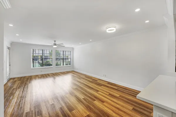 a view of kitchen and empty room with wooden floor
