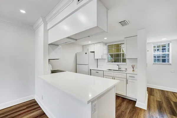 a kitchen with a refrigerator a sink and white cabinets