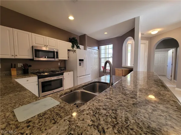 a kitchen with stainless steel appliances granite countertop a stove a sink and a microwave