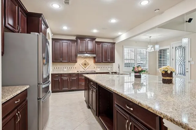 a kitchen with stainless steel appliances granite countertop a sink refrigerator and cabinets